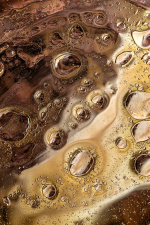 Deep brown and amber abstract macro photography of oil bubbles and fluid textures, creating a rich...