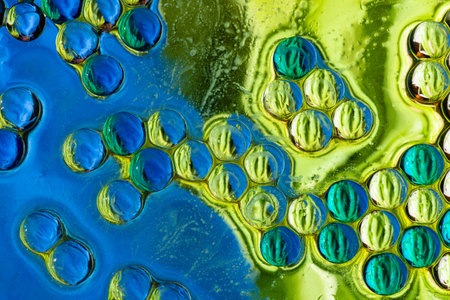 High quality macro photography of blue and green oil bubbles creating a dense cellular pattern and...