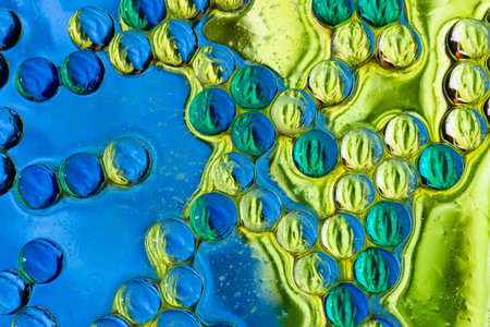 High quality macro photography of blue and green oil bubbles creating a dense cellular pattern and...
