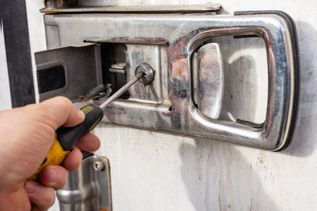 Close up of unauthorized person trying to force open a heavy truck door lock for cargo theft...