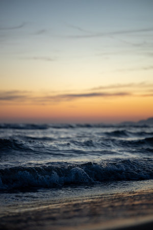 Sunset over ocean waves with a serene sky.
