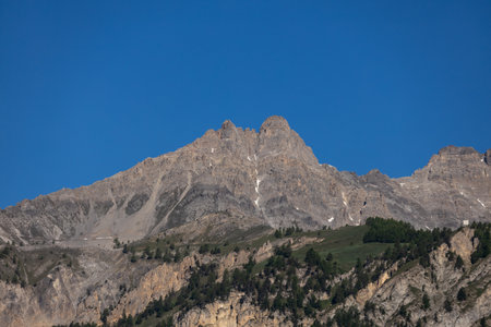 Rocky mountain peak under clear blue sky with sparse vegetation.の写真素材