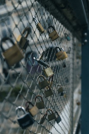 Close-up of love locks attached to a metal fence on a bridge.の写真素材