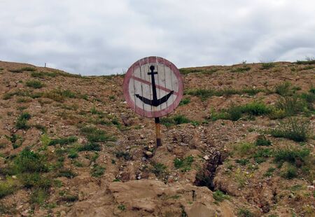 The underwater crossing sign for river vessels "Do not drop anchor", installed on the shores of a clay, brown shore. River "Western Dvina", the city of Vitebsk, Belarusの写真素材