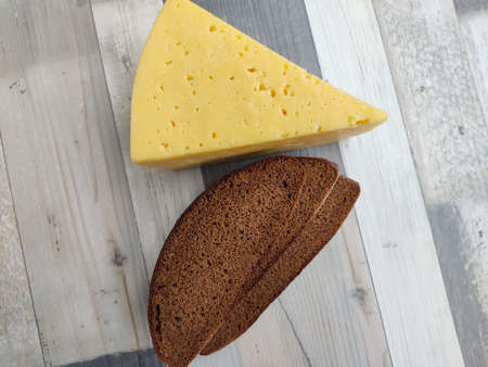 Goladian yellow cheese close-up on a table top with slices of black bread. Fresh dairy products, healthy organic products. Delicious appetizer. Macro photography.の写真素材