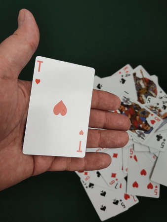 The mans hand throws a deck of cards onto the game table.