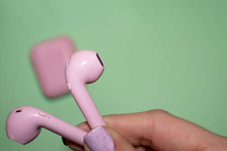 Wireless headphones in a hand on a mint background. The concept of technology and progress.
