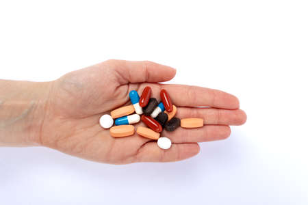 Handful of pills in hand isolated on a white background. Medicine concept.