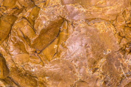 Background of a large orange crushed stone. Torn stone. The surface of the cut stone. Close photographed rock of stoneの写真素材