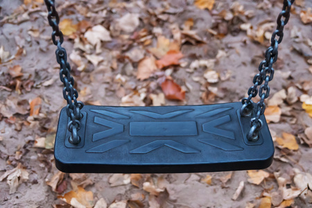 Abandoned swing on a playground with leaves in autumの写真素材