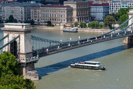 Chain bridge and tourist boat in Budapest at Danube river on a sunny dayの写真素材