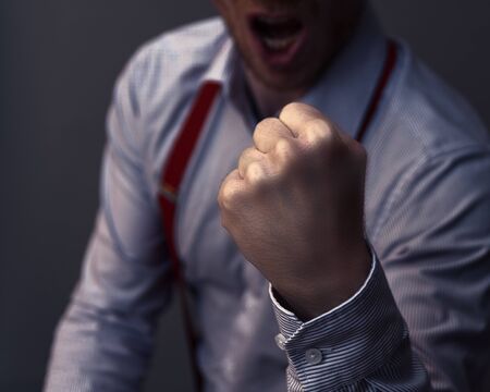 Businessman clenches his fist and is aggressive or celebrates his success