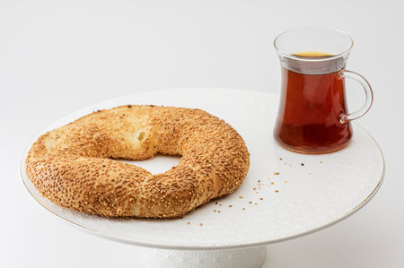 Crispy Turkish traditional bagel, bagel with sesame and glass of turkish black tea, turkish breakfast pastry concept. Turkish tea in traditional glass cup.の写真素材