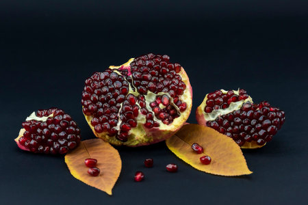 Ripe pomegranate fruit on a black background with leavesの写真素材