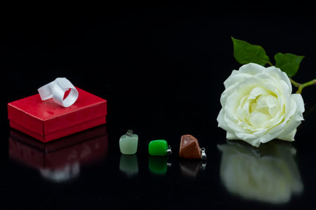 Red gift box and white rose on a black background with reflection.の写真素材