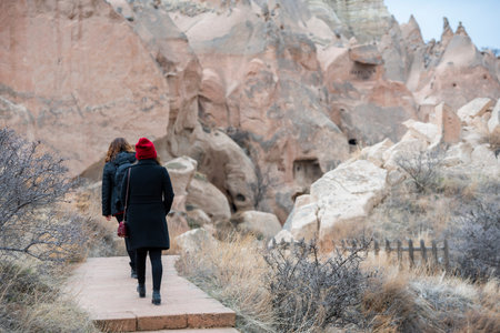 A young woman in a black coat and red hat stands on a stone path in Cappadocia, Turkey.の写真素材