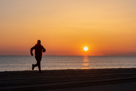 Runner athlete running on beach at sunrise or sunset. man fitness jogging workout wellness concept.の写真素材