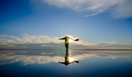 Silhouette of woman doing yoga on a salt lake at sunsetの写真素材