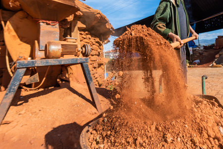 Worker pouring sand on a construction site with a cement mixer.