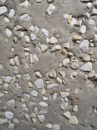 A lot of small white pebbles in porous gray concrete, textureの写真素材
