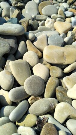Large gray coastal pebbles lit by the warm summer sun, backgroundの写真素材
