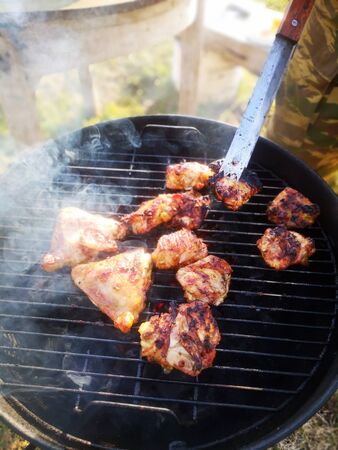 On the grill are roast pieces of meat, smoke is coming and red coals are visibleの写真素材