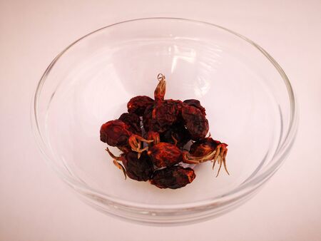 Appetizing dried rosehip lies in a transparent plate on a white backgroundの写真素材