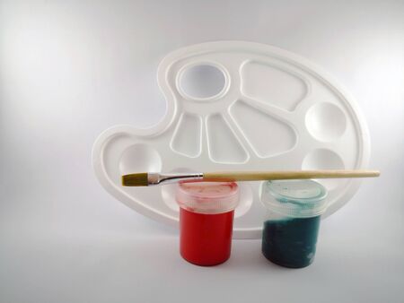 Gouache of different colors with a palette and a brush on a white backgroundの写真素材