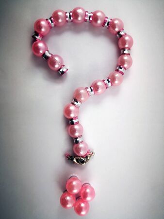 A question mark lined with pink women's beads on a white background. Isolate. Question mark.の写真素材