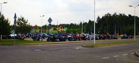 Many motorcycles of various colors and styles are parked in the same parking lotの写真素材