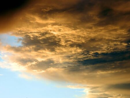 A veil of gray thunderclouds obscures the blue skyの写真素材