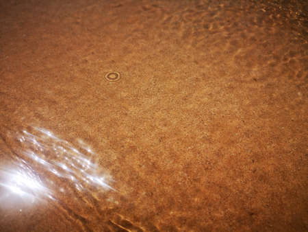 Golden sand can be seen through the water with a beautiful pattern. Abstract texture.の写真素材