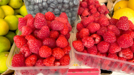 Raspberries and blueberries in containers. Foodstuffs and fruits. Harvest and market. Healthy...