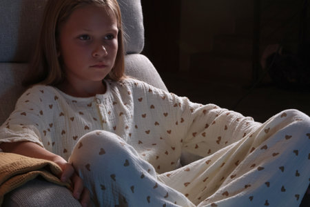 Schoolgirl watching movie in living room in pajamas in evening. Modern interior and reclining rocking chair. Exciting pastime. . High quality photoの写真素材