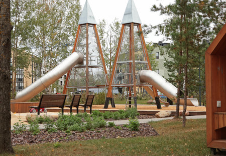Modern childrens playground with slide. Nature and recreation. Clean residential complex in forest among coniferous trees. . High quality photoの写真素材