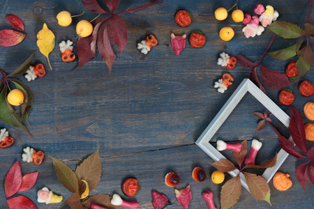 Frame of fall leaves, candy for Halloween. Holidays and food. Dessert in the shape of a pumpkin,...