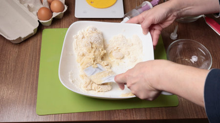Process of making dough. Woman mixed powdered sugar, almond flour and egg white with silicone...