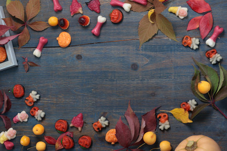 Frame of fall leaves, candy for Halloween. Holidays and food. Dessert in the shape of a pumpkin,...