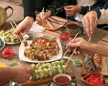 Sushi sets, sauce, wasabi, tea on holiday table. Food and traditional dishes of Asian cuisine. People take rolls with chopsticks. Table setting. . High quality photoの写真素材