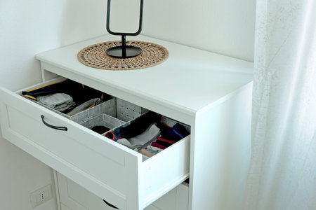 White bedroom dresser with table mirror near window. Furniture and interior in Scandinavian style....