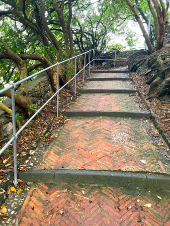 Brick old steps on path up hill amongst trees. Ancient building. Traditional park in Italy, Liguria....