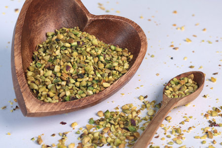 Crushed pistachio nuts in wooden bowl and heart-shaped spoon for cooking. Environmentally friendly product and health. High quality photoの写真素材