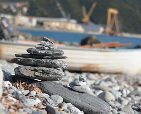 Big and small pyramid of marble stones against mountain backdrop on sunny day. Balance of mental health and meditation. Caring for body.の写真素材