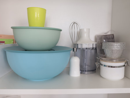 Storage in cupboards on shelves in kitchen at home. Crockery, plastic containers, electrical...