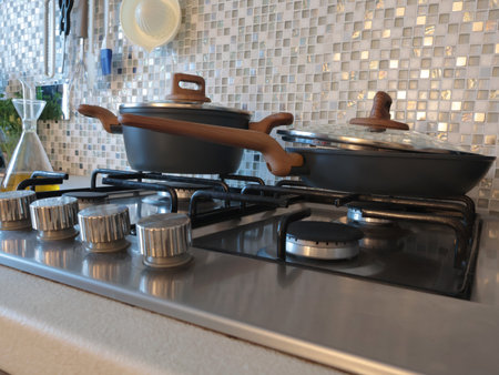 Modern frying pan and saucepan with lids on gas stove in kitchen. Mosaic tiles and worktop. Interior design of flat. . High quality photoの写真素材