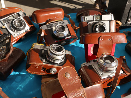 Vintage Leather Cameras on Market Stall. Assortment of old leather-cased analog cameras on blue...