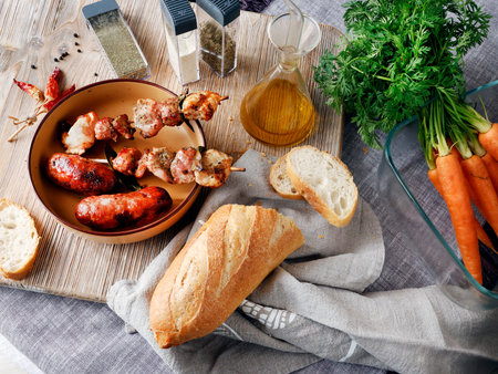 Composition of grilled sausages and pieces of meat on wooden skewer. Seasonal farm produce, vegetable, and bread. Homemade food. Designer background. High quality photoの写真素材
