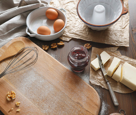 Wooden cutting board with flour copy space and baking ingredients. High angle shot of rustic kitchen...