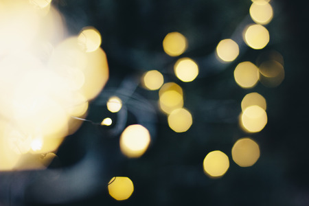 A beautiful image of a bokeh from New Years garlands. In gold colors. Defocused glitter lighting image for art and design.の写真素材