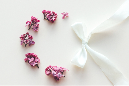 Flower frame on white background. Lilac flowers and a white satin ribbon bow.の写真素材